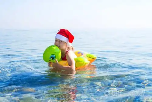 小女孩在海上游泳, 在圣诞老人帽子的充气戒指, 自由空间.