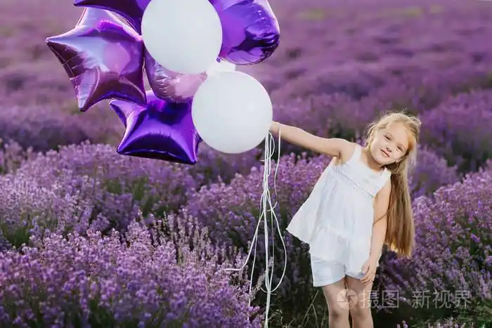 照片 快乐可爱的小女孩在薰衣草领域与紫色气球.自由概念.jpg