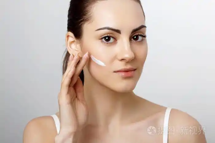 女人面对皮肤护理. 有吸引力的年轻女性的肖像,涂抹奶油和拿瓶.