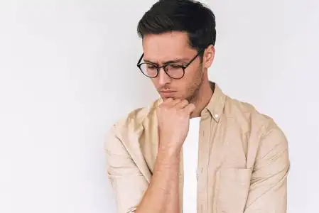 陷入思考年轻的白人男子托住下巴,陷入沉思,低头,穿着休闲装,在白色