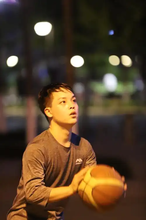 抓拍夜间路灯下街头篮球,人物投篮后的瞬间表情,原图无任何后期.