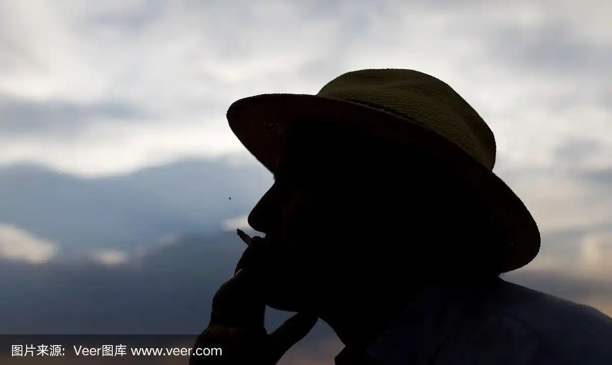 在日落的背景上,一个男人吸烟的剪影