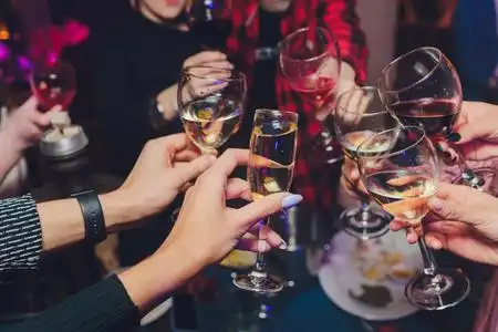 一组人在博克背景前用葡萄酒或香槟碰杯的特写镜头.老年人的手.照片
