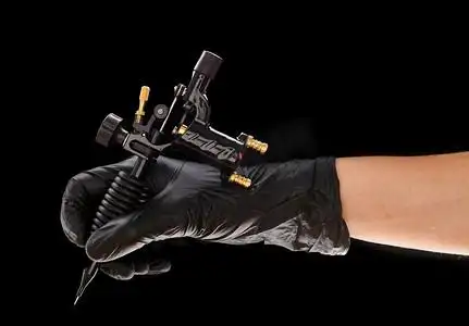 艺术家手中的纹身机在黑色背景下被隔离吊坠工艺品