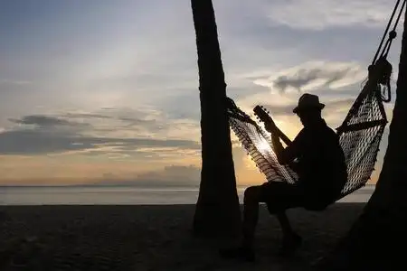 在沙滩上与夕阳弹吉他的男人照片
