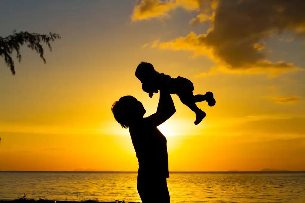 母亲和小儿子剪影,母亲和日落海滩上的小儿子剪影