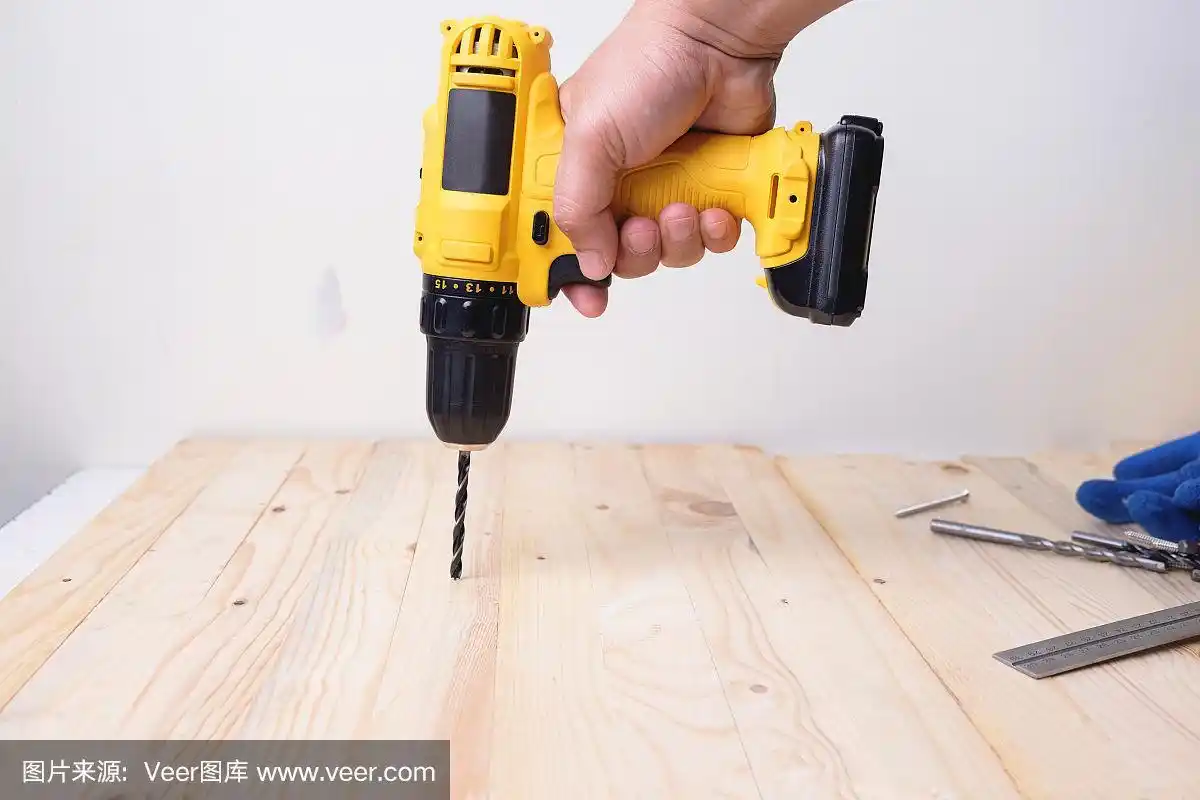用电钻在木板上工作的工匠