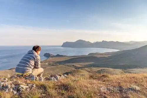 人坐在岩石上的山上的城市沉思和观看日落