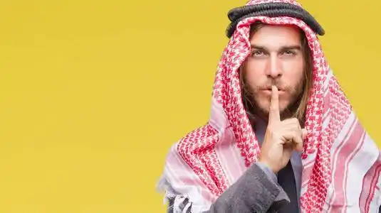 留着长发,戴着keffiyeh,在孤立的背景下,要求嘴唇上用手指保持安静