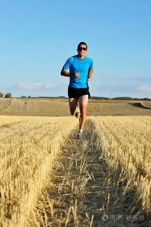 运动男戴太阳镜在草地上户外跑步