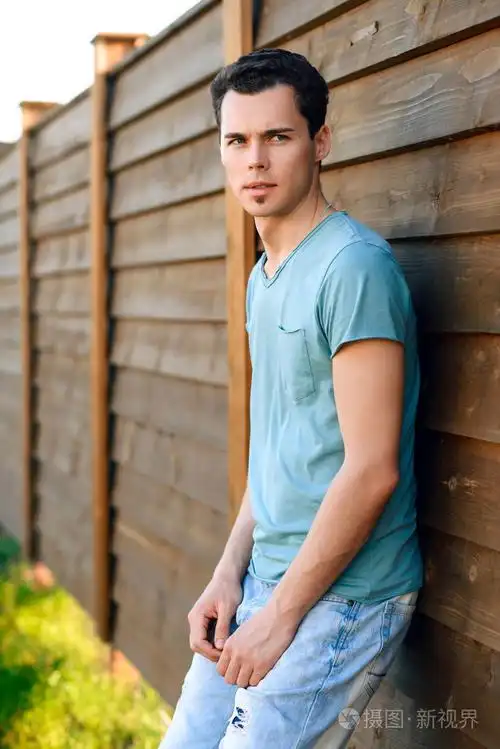 猛男年轻的帅小伙,室外在日落时一件蓝色衬衫的肖像照片-正版商用图片