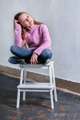 时尚的儿童女孩坐在椅子上的时尚姿势.