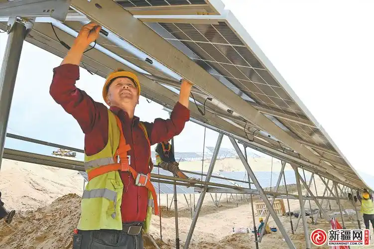 近日,在米东区北部沙漠光伏基地,工人正在搭建安装光伏板.
