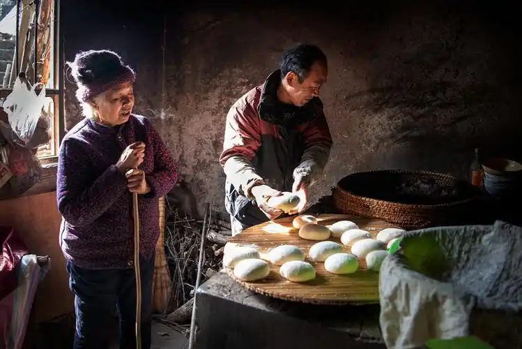 年2月1日拍摄于河南省南召县城郊乡大庄村,一贫困户母亲教儿子蒸馒头