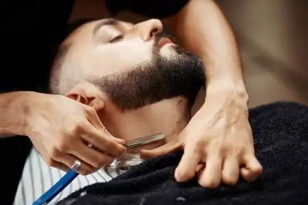 匿名男子剃须客户端男理发师的梳理和剃光头发的男性客户端皂洗和在