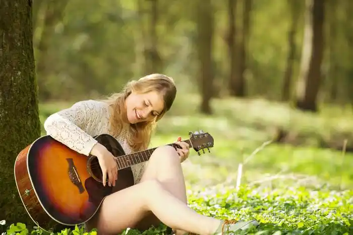一个美丽的年轻女人弹吉他户外的肖像