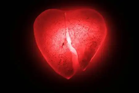 半黑暗冰冻成半心形象征着一个明亮的红色特写镜头在黑暗中发光.