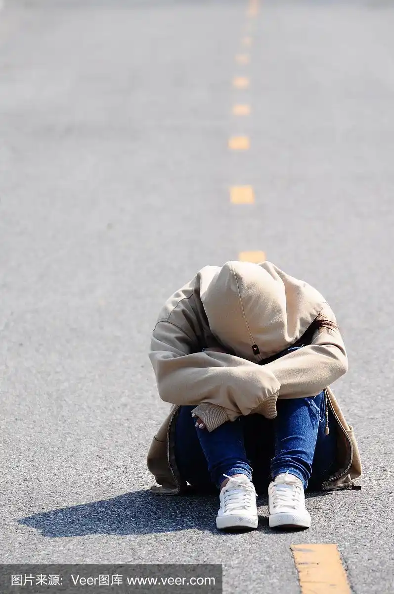 伤心哭泣的女人抱着她的膝盖在路上