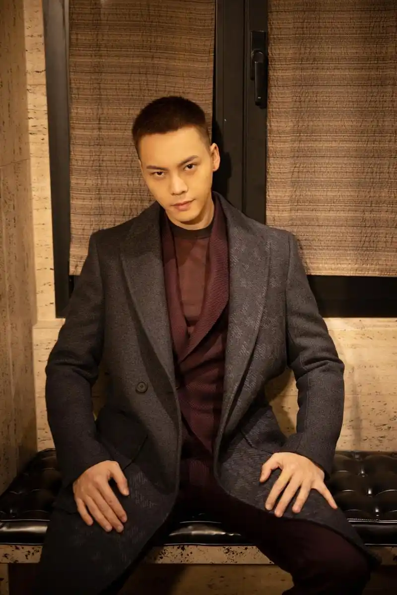 陈伟霆出席米兰男装周看秀,身着枣红色翻领西装外搭灰色翻领大衣,将