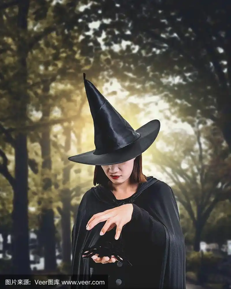 在黑暗的森林里,一个可怕的女巫万圣节服装手持黑蜘蛛与月光
