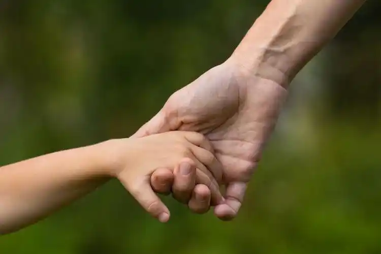 草地上母亲拉着孩子的手