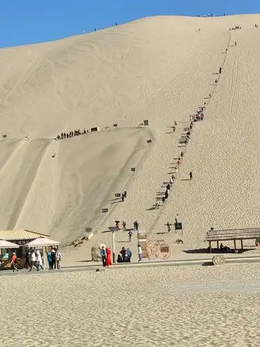 游人在鸣沙山上滑沙.