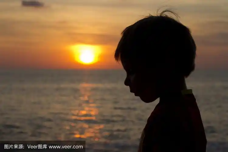 日落时海滩上一个孩子的侧面剪影