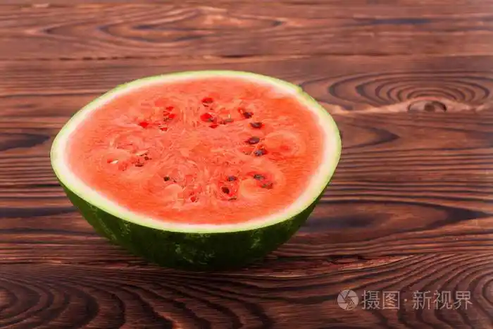 一个成熟多汁美味西瓜切两半上深色的棕色木制背景西瓜瓤是甜的皮是