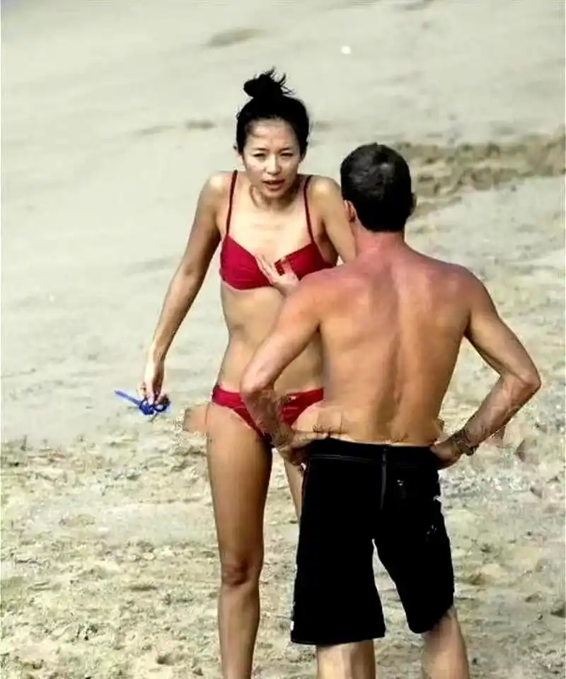章子怡和她的外籍前男友在沙滩上玩耍,她瘦弱的身材和两人紧握的手指