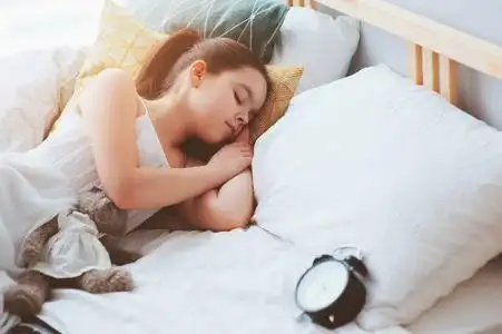 起床困小女孩清晨睡在床上, 闹钟, 起床和上学的时间照片