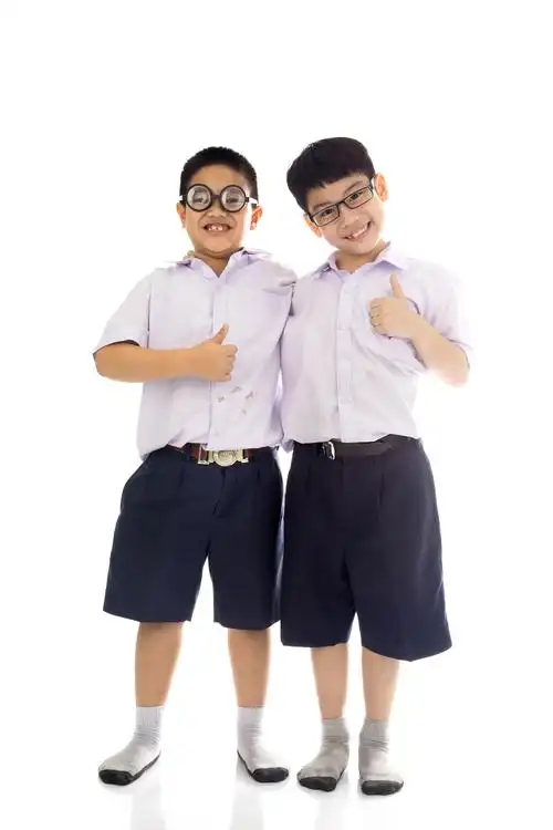 白色背景下全身照的两个小学生亚洲小学的学生从学校,衣衫回来