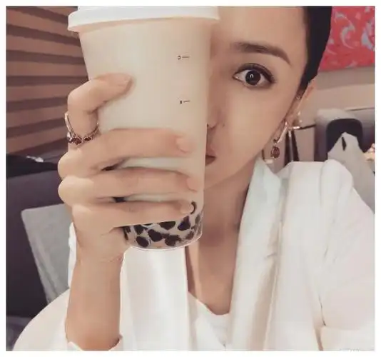 戴着首饰妆容精致,奶茶遮住了大半张脸,显得人愈发小巧