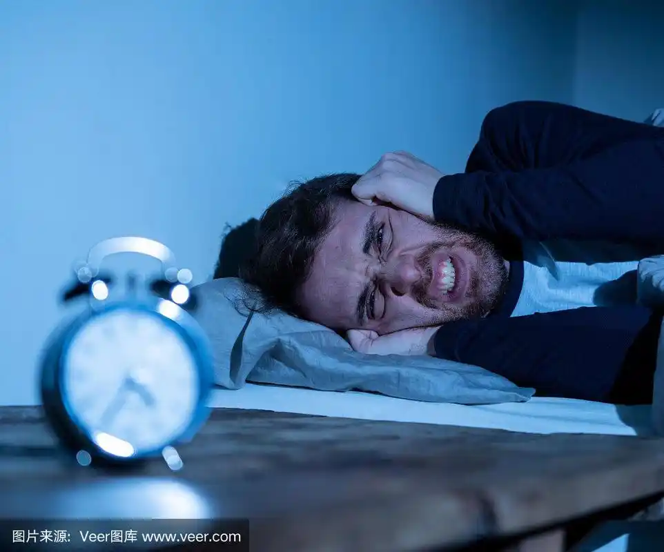 失眠和绝望的年轻白种人晚上醒来不能睡觉,感觉沮丧和担心看时钟遭受