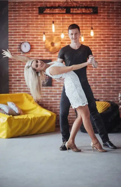 年轻夫妇在跳拉丁舞曲bachatamerenguesalsa两个优雅的姿势在有砖墙的