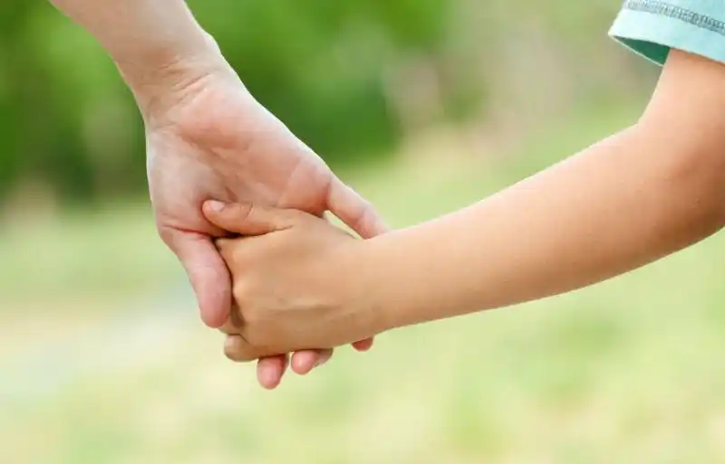 草地上母亲拉着孩子的手