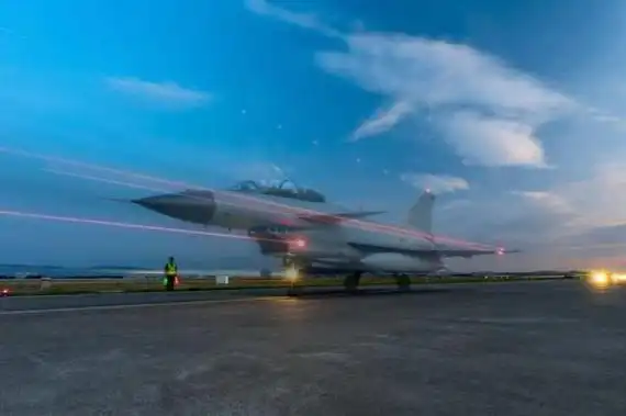 南部战区空军某旅机场上,保障车辆来回穿梭,机务官兵在机翼下精心维护