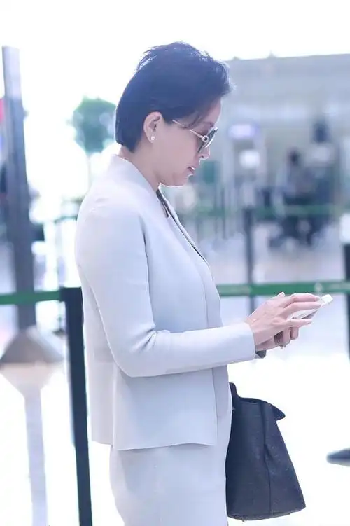 主持人杨澜51岁了,穿西裙套装走机场气质出众,可惜双下巴显老态