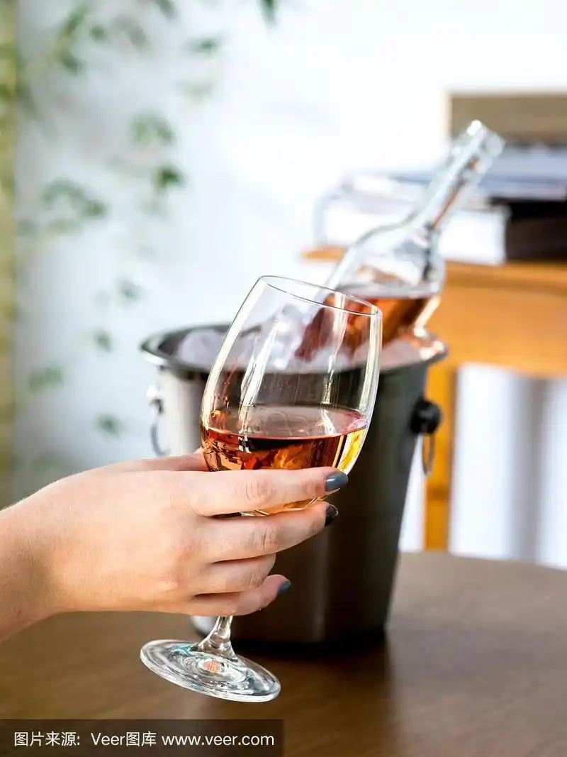 在酒吧餐厅,手里拿着酒杯,桌上放着酒瓶