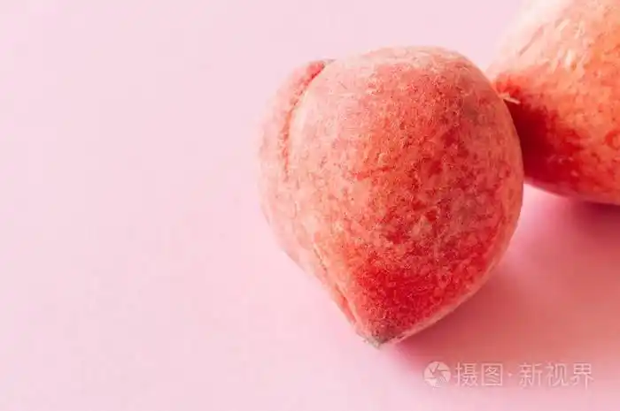 两个新鲜成熟的桃子在粉红色的背景有机食品概念特写