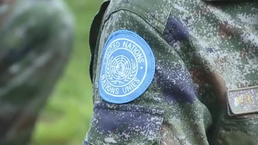 脚蹬棕色新式作战靴,身着星空迷彩,头戴蓝色贝雷帽,佩戴"un"臂章,胸前