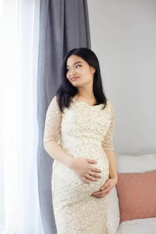 照片 美丽的年轻亚洲孕妇站在窗口和触摸她的肚子.怀孕.健康.母亲.