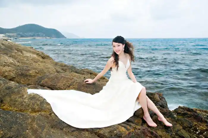 纯洁的白纱 俏美的卷发 柔柔的笑着坐在海边礁石上,耐心的等待