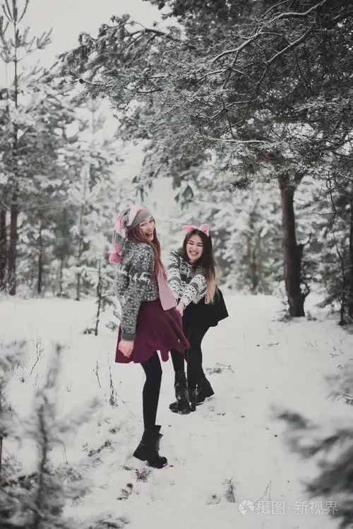 关闭了时尚肖像的两姐妹拥抱和乐趣,走在冬天时间森林,穿着粉红色的