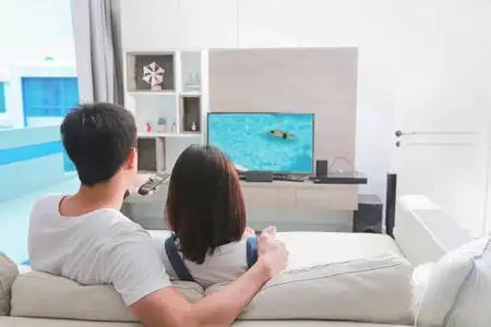 幸福的家庭坐在沙发上看电视照片