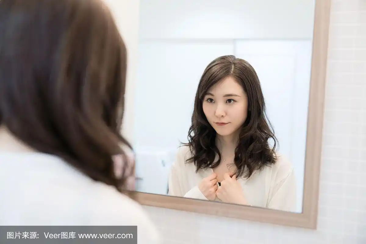 年轻的亚洲女人照镜子.