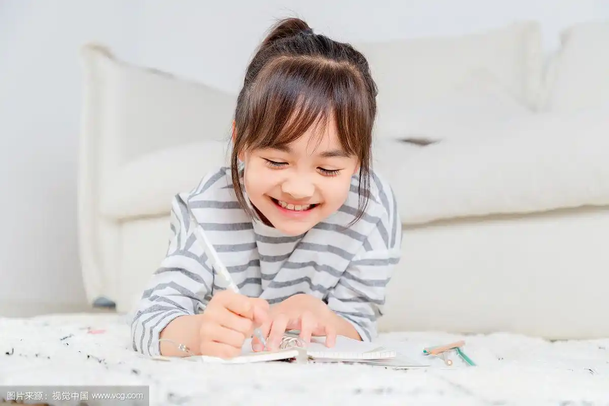 趴在地毯上写字的亚洲小女孩