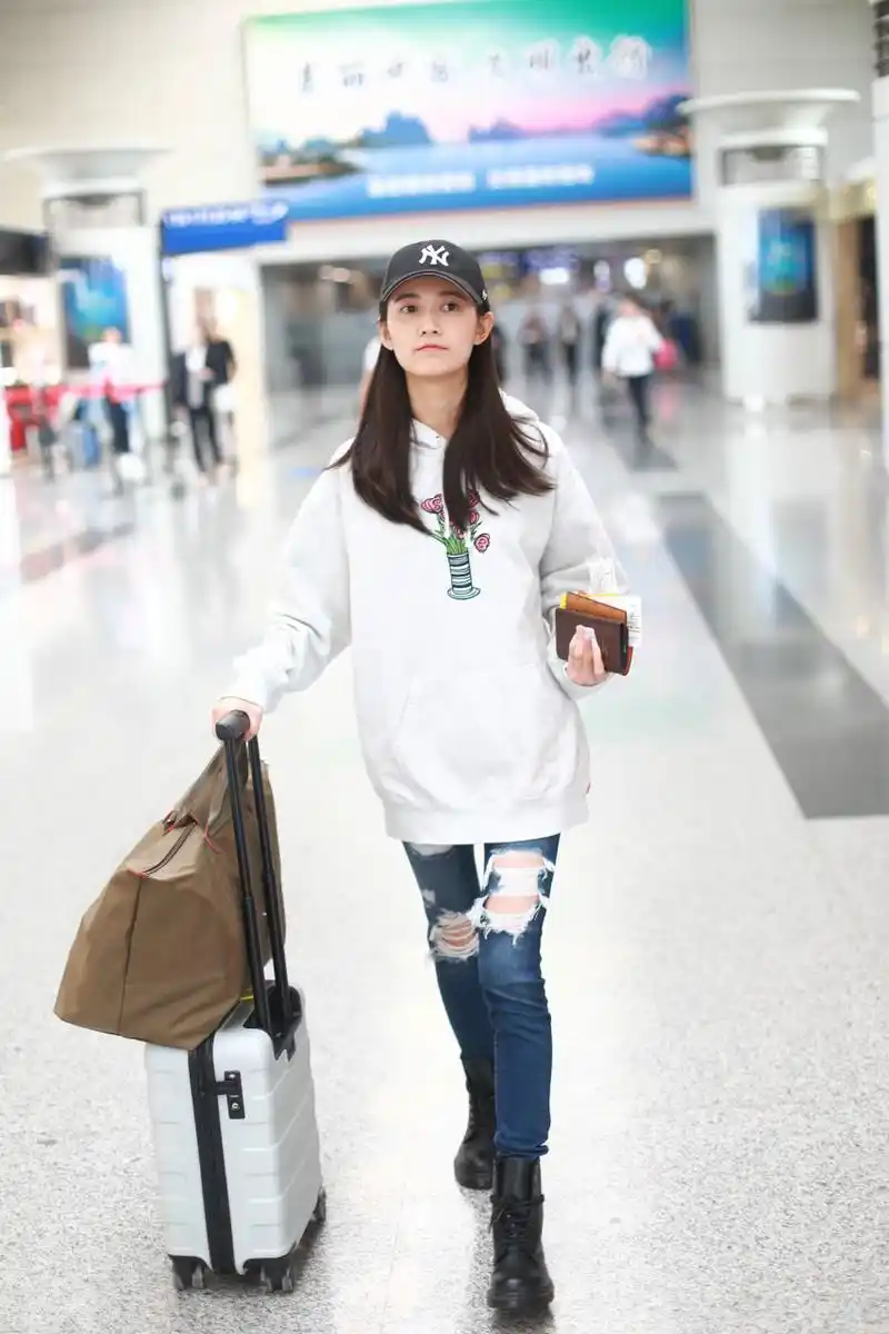陈钰琪穿白色卫衣搭配破洞牛仔裤现身机场,戴黑色棒球帽皮肤白皙