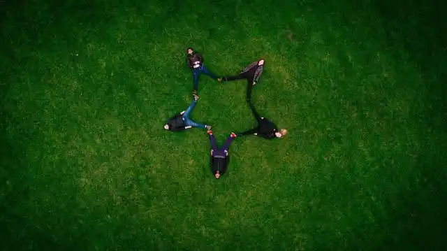 绿色旅游自然五个人躺在草地上摆出星型团队建设