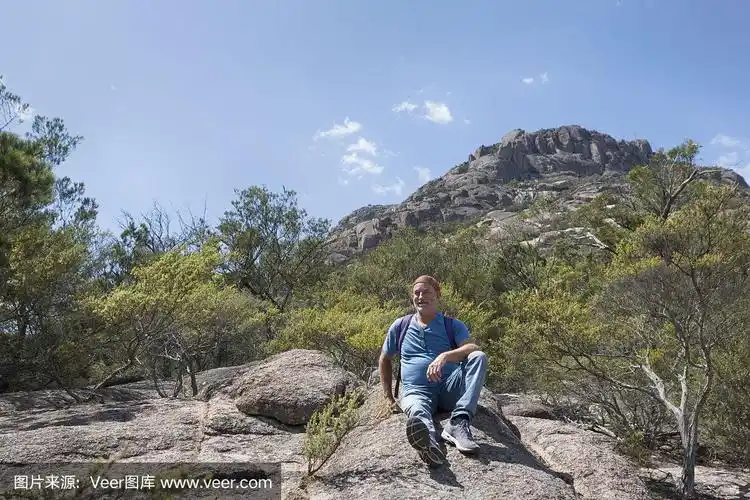 一个成熟的男人坐在岩石上休息.