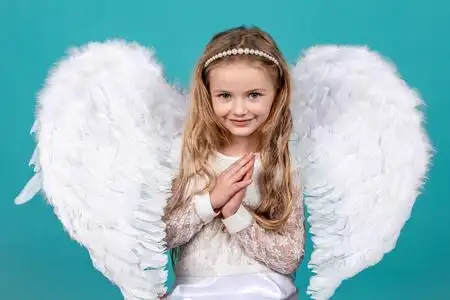 美丽的小天使女孩站在你的手臂靠近你的胸部祈祷.天使们双手交叉照片